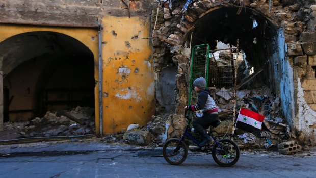 A Syrian boy rides his bike past the destruction in the once rebel-held Jalloum suburb of eastern Aleppo, Syria.