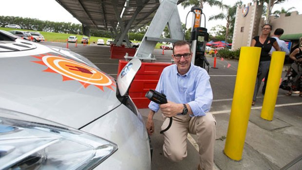 Tony Gilding, owner of the Macadamia Castle, charges an electric car at a new solar panel charging station. 