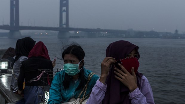 Wearing faces masks in Palembang, Indonesia, as haze shrouded the Ampera bridge on the weekend.