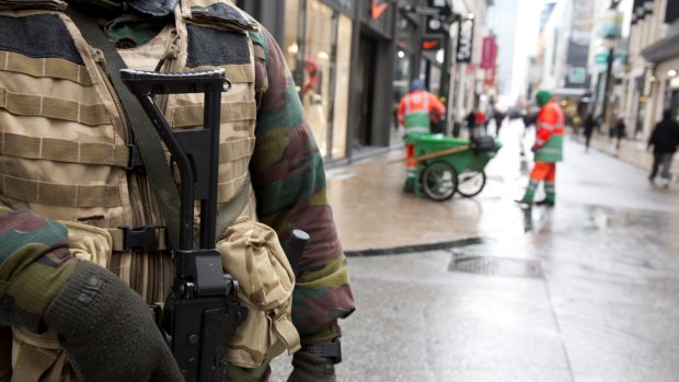 A Belgian Army soldier patrols an otherwise busy shopping street in Brussels on Saturday following the lock down.