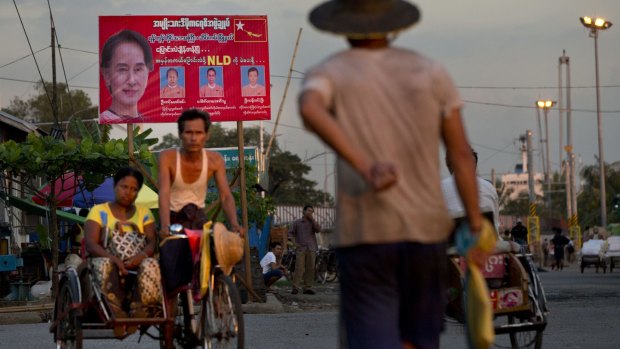 A man rides a rickshaw in the foreground of a billboard promoting candidates of  Myanmar's opposition leader Aung San Suu Kyi's National League for Democracy party in Yangon on Wednesday.