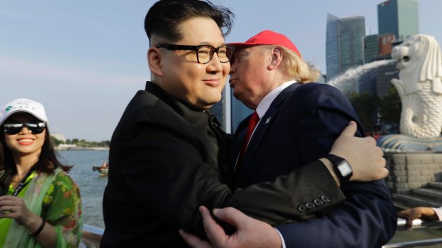 A tourist looks on as Kim Jong Un and Donald Trump impersonators, Howard X, center, and Dennis Alan, right, embrace in Singapore.