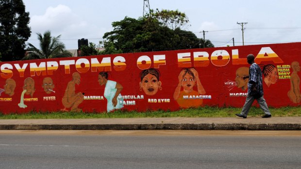 A man walks by a health information mural in Monrovia, Liberia.