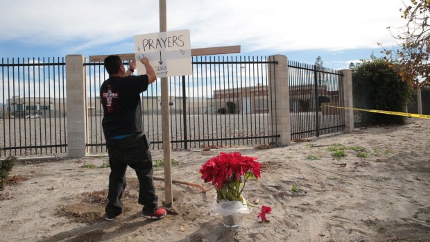 A cross and a sign outside the police perimeter around the Inland Regional Centre, the site of a mass shooting that left 14 dead and 21 wounded, in San Bernardino, California.