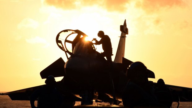 A French navy soldier prepares a Rafale fighter aircraft on board the aircraft carrier Charles de Gaulle ahead of deployment to the Persian Gulf to support operations against the so-called Islamic State.