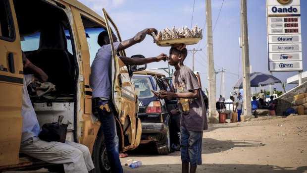 Drivers buy food while waiting in line for fuel in Lagos.