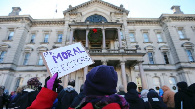 A protester holds up a sign as a group demonstrates in freezing temperatures at the New Jersey Statehouse, ahead of the Electoral College on Monday.