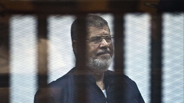 Egypt's ousted Islamist president Mohamed Morsi stands behind bars in Cairo on Tuesday.