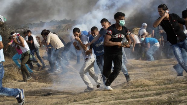 Palestinian protesters run for cover from tear gas fired by Israeli soldiers during clashes on the Israeli border with Gaza east of Bureij refugee camp on Friday. 