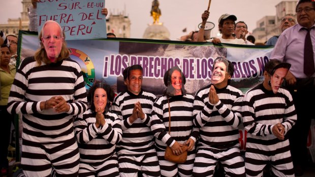 People wearing masks of Peruvian politicians pretend to be prisoners during a protest calling for justice after the Odebrecht corruption scandal in Lima, Peru,.