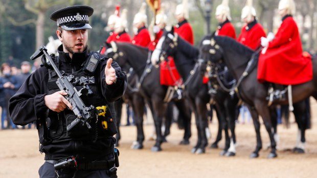 An armed British police officer patrols in Horse Guards Parade.
