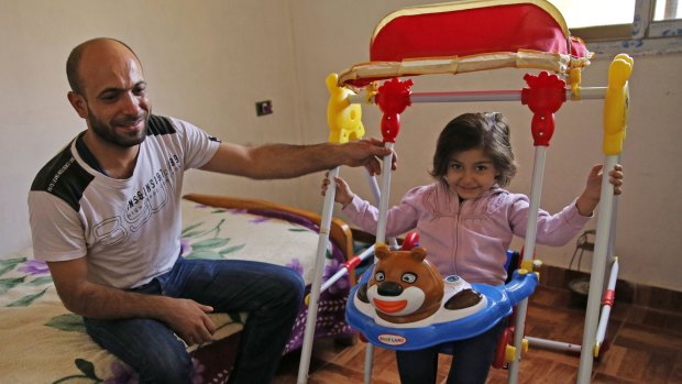 Abdul Halim al-Attar, a refugee from Syria sits next to his daughter Reem, 4, at his house in Beirut.
