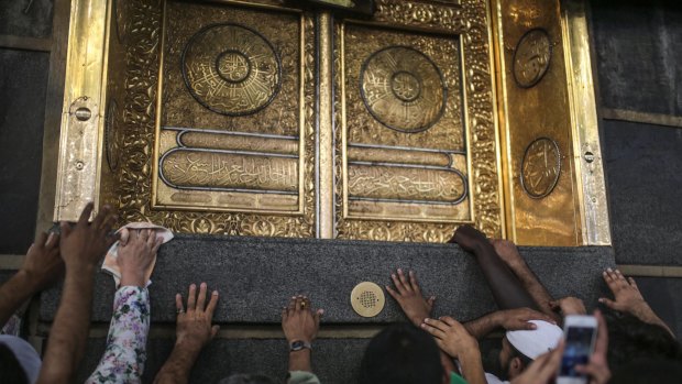 Muslim pilgrims pray as they touch the Kaaba, the cubic building at the Grand Mosque in Mecca on Monday.