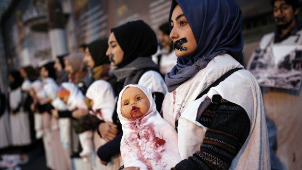 Turkish women from pro-Islamist groups hold painted dolls depicting dead Syrian babies as they protest against the war in Syria in Istanbul on Thursday.