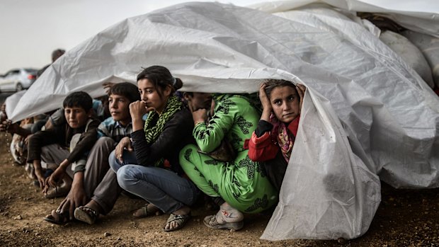 Fear: Syrian Kurds take cover after crossing the border between Syria and Turkey in October, fleeing the Islamic State fighters.