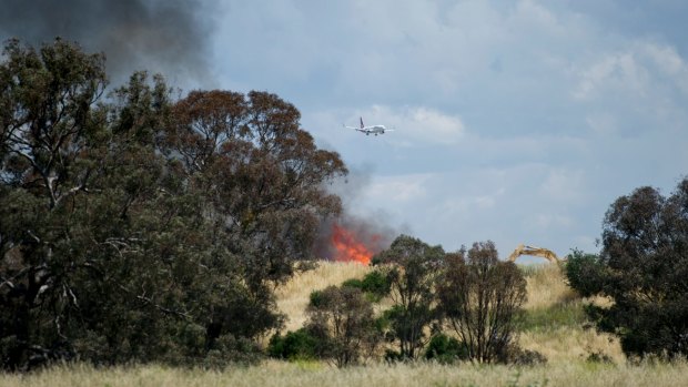 A view of the rubbish fire at the waste recycling facility in Pialligo, with an aircraft in the background.