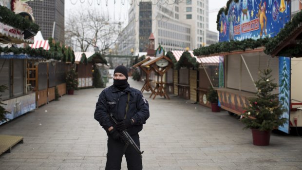An armed police officer stands guard as the festive stalls remain closed at Berlin Christmas market in Berlin, Germany after a terror attack last year.