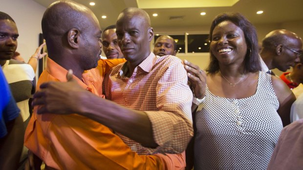 Presidential candidate Jovenel Moise, centre, from the PHTK, greets a supporter accompanied by his wife Martine, right.