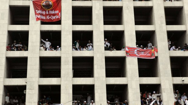 People join the protests from their windows in Jakarta.