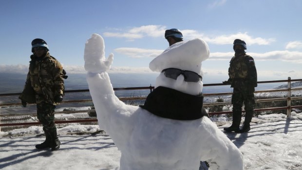 A friendly snowman is flanked by UN peacekeepers near the Lebanese-Israeli border.