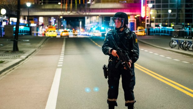 An officer stands guard as police cordon off a large area in Oslo around a subway station on a busy commercial street Saturday night.