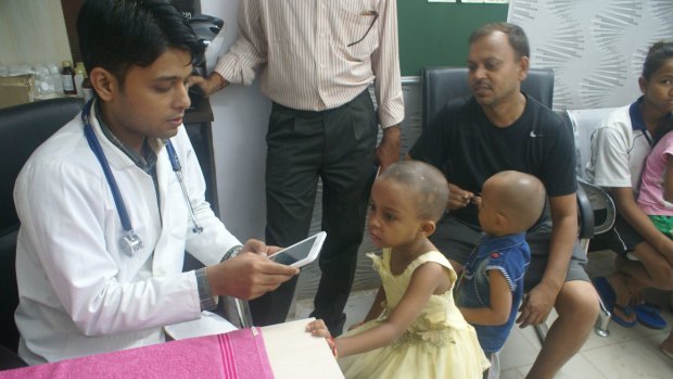 Dr Shoebul Haque checks the medical records of Mohan Gupta's daughter Priya on a tablet device.  