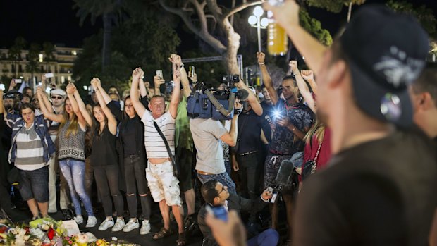 People sing the French national anthem at a makeshift memorial in Nice.