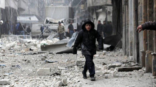 A boy walks on debris at a site hit by what activists said were two barrel bombs dropped by forces loyal to Syrian President Bashar al-Assad in February.