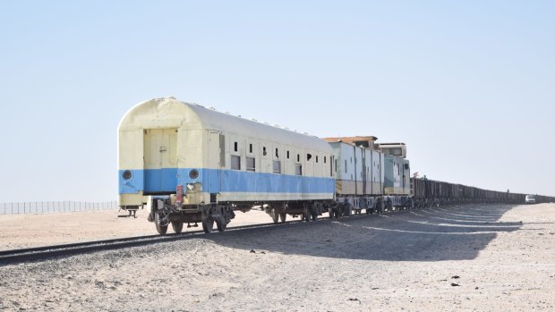 A passenger carriage brings up the rear of the immensely long freight train.