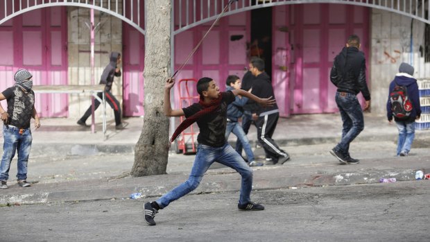 A Palestinian youth hurls stones with a slingshot at Israeli troops during clashes in Hebron on Wednesday. 