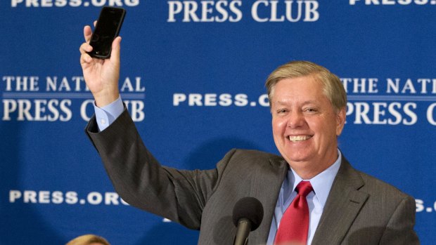 Republican presidential candidate Senator Lindsey Graham, holds up his cell phone after the moderator mentioned Donald Trumps prank in giving out Graham's cell phone number at a press conference.