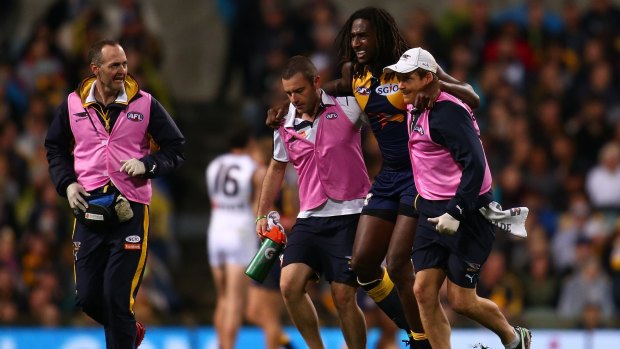 Nic Naitanui is assisted from the field with a knee injury during the clash with Hawthorn.