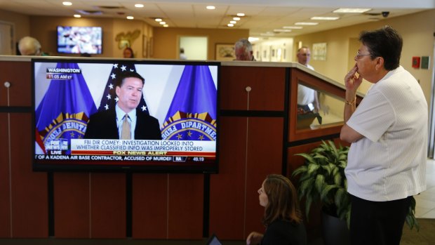 A woman watches as James Comey announces the results of his department's investigation into Hillary Clinton's handling of classified emails.