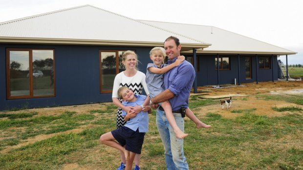 The Kelk family of Murrumbateman: Brad and Fiona with their children Jack ,8, and Aimee, 6, with the new house they are building "off the electricity grid" behind them. 