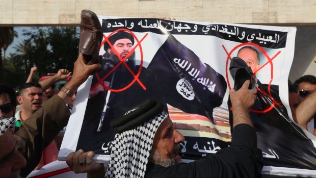 Protesters carry defaced posters of Islamic State leader Abu Bakr al-Baghdadi, left, and Iraqi Defence Minister Khaled al-Obeidi, right, as they chant slogans against the Islamic State group during a protest in Baghdad.