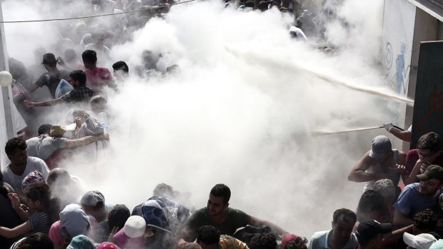 Policemen try to disperse hundreds of migrants by spraying them with fire extinguishers, during a registration procedure at the stadium of Kos, Greece, on Tuesday.