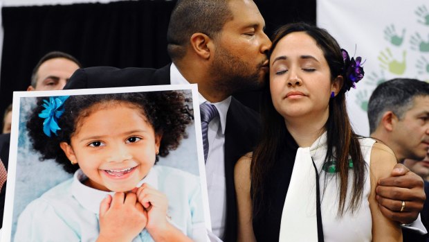 Jimmy Greene, left, kisses his wife Nelba Marquez-Greene while holding a portrait of their daughter, Sandy Hook Elementary School shooting victim Ana Marquez-Greene, at a news conference in 2013.