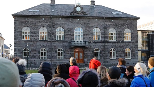 People stand outside the Icelandic parliament the Althing in Reykjavik. Iceland will be the first country in the world to make employers prove they offer equal pay regardless of gender, ethnicity, sexuality or nationality.