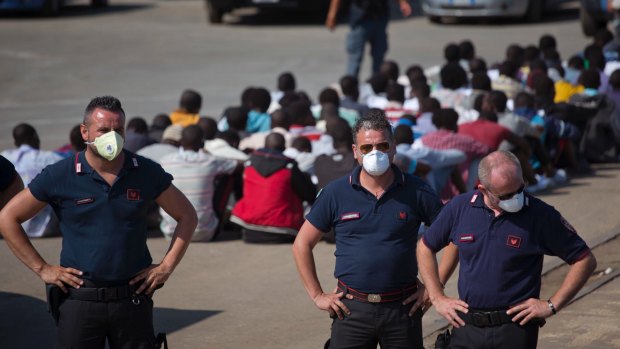 Italian border police stand next to sub Saharan men arriving at the port of Augusta, in Sicily, Italy, last month.