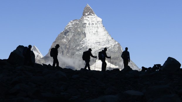 Hikers cross in front of Switzerland's famous Matterhorn mountain.