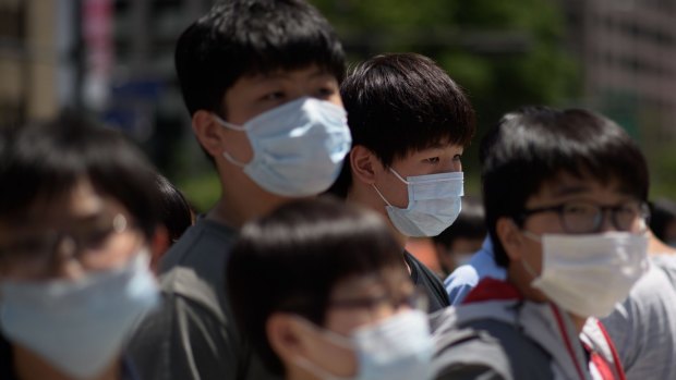 Students wearing face masks wait to cross a street in Seoul on June 3.