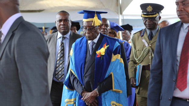 President Robert Mugabe, centre, leaves after presiding over a student graduation ceremony at Zimbabwe Open University on the outskirts of Harare on Friday.