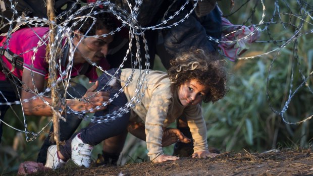 A child is helped cross from Serbia to Hungary through the barbed wire fence near Roszke, southern Hungary, on Thursday.