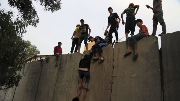 Supporters of Shiite cleric Muqtada al-Sadr climb over the blast walls outside Baghdad's Green Zone.