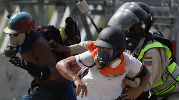 Anti-government protesters run from police in Caracas on Wednesday.