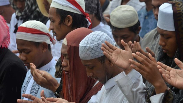 Demonstrators pray in the rain at the December 2 rally against Ahok.