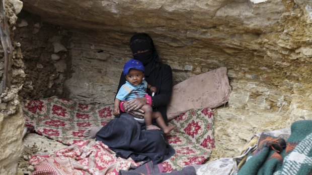 An internally displaced woman sits with a child in a cave in the district of Khamir of Yemen's north-western province of Amran.