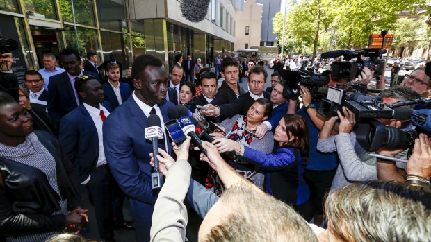 Majak Daw surrounded by reporters and photographers outside the County Court.