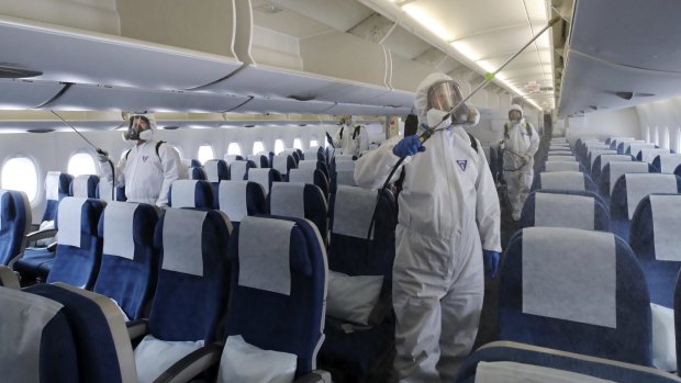 Workers wearing protective gears spray disinfectant inside a plane for New York at Incheon International Airport in Incheon, South Korea on March 4, 2020.