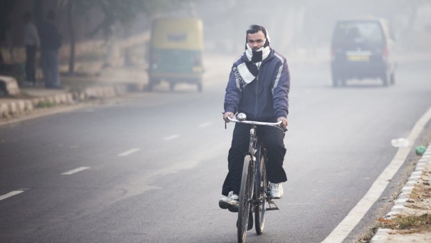 A cyclist travels along a road shrouded in smog in New Delhi, India.